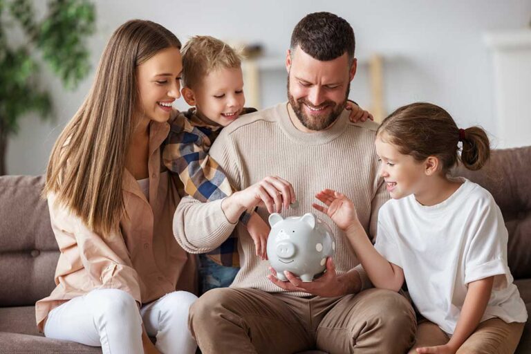 A parent and child counting coins together at a kitchen table with a small savings jar nearby.