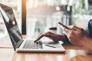 Resident reviews a banking app on a locked smartphone beside a notebook and home Wi-Fi router.